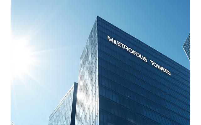 Exterior of the 'Metropolis Towers' office building, a modern skyscraper with reflective glass.